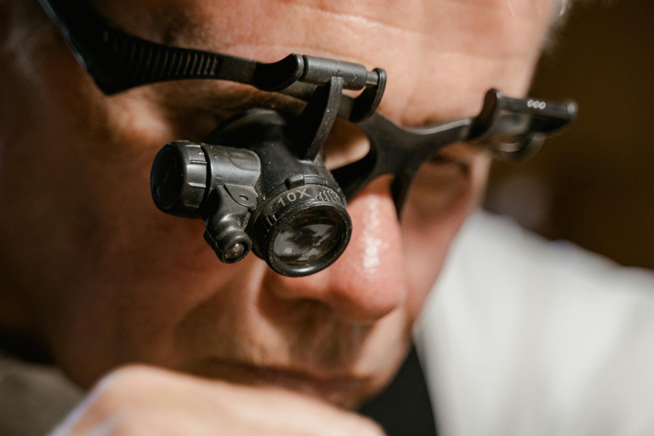 A close-up of a jeweller wearing magnifying glasses