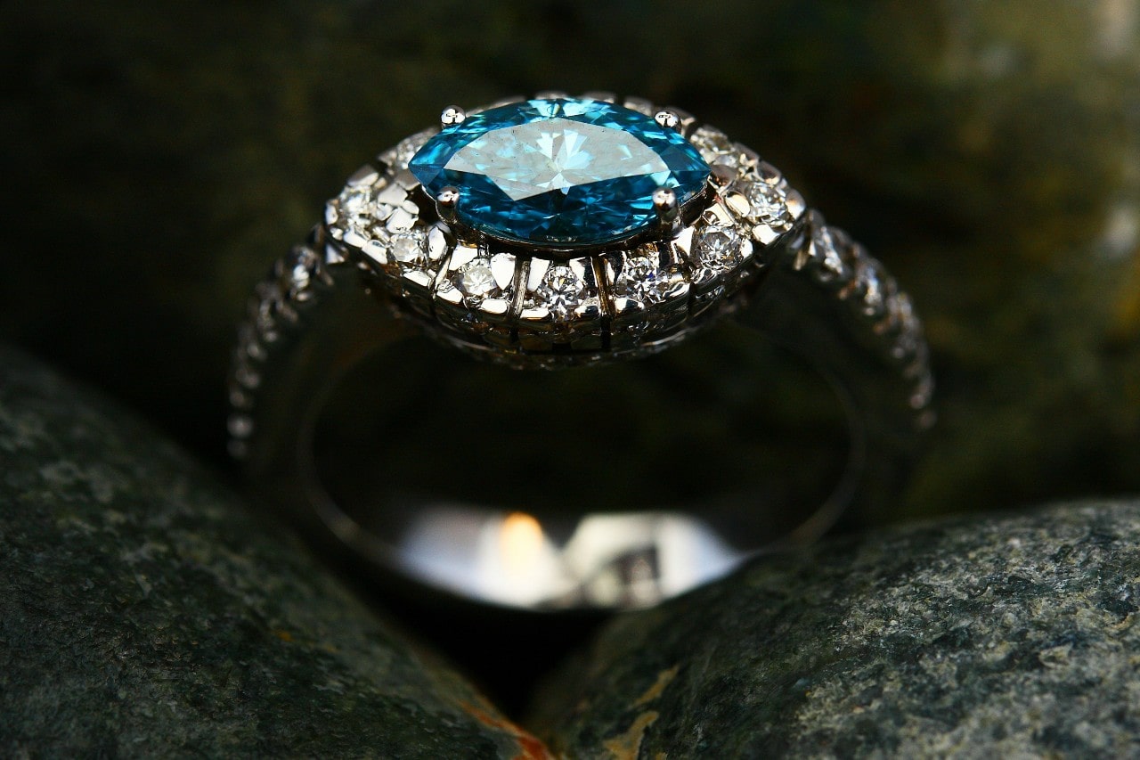 A close-up of a white gold engagement ring with a blue marquise cut centre stone.