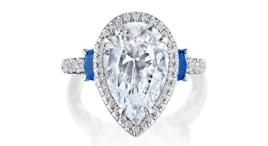 A white gold engagement ring with a pear shape centre stone and sapphire stones, available at GMG Jewellers.